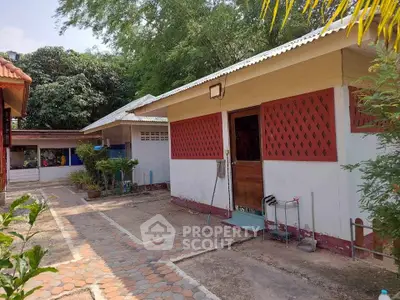 Charming single-story home with unique lattice windows and lush greenery, perfect for serene living.