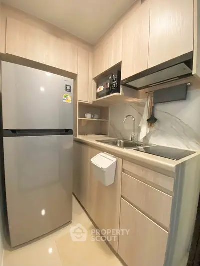 Modern compact kitchen with sleek cabinetry and stainless steel appliances in a cozy apartment.