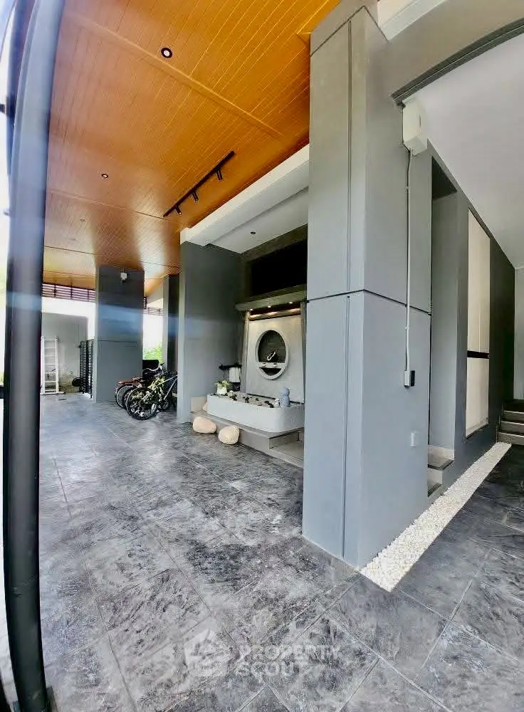Modern covered parking area with sleek design and bicycles, featuring stylish gray walls and wooden ceiling.