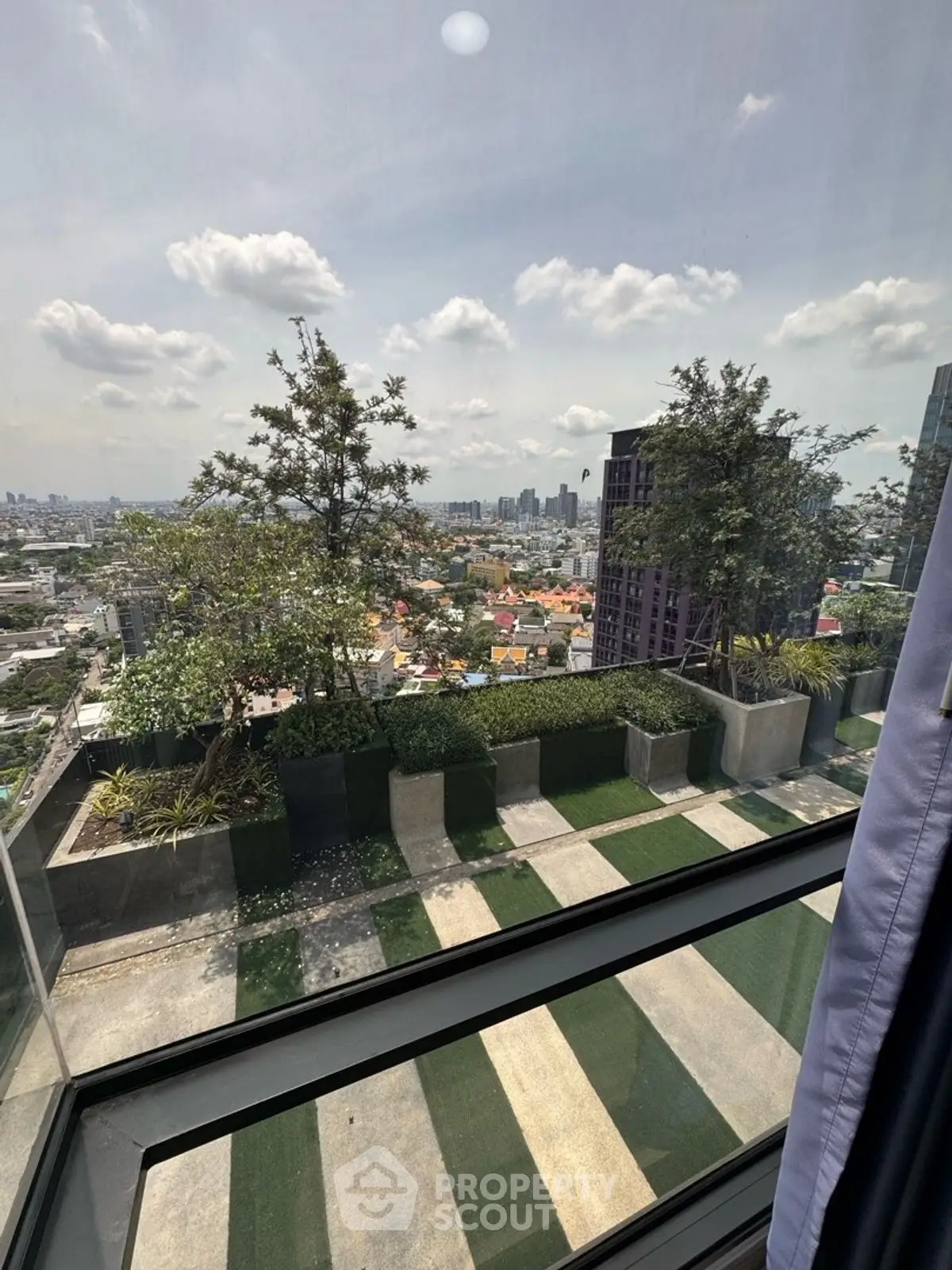 Stunning cityscape view from high-rise balcony with lush greenery and skyline.
