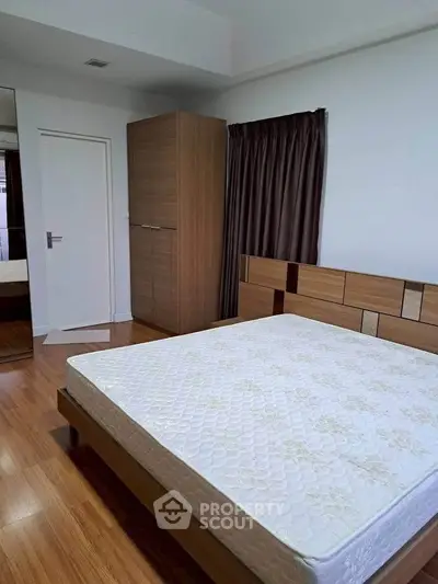 Spacious bedroom with modern wooden furniture and large window.