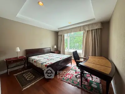 Spacious bedroom with elegant wooden furniture and large window view.