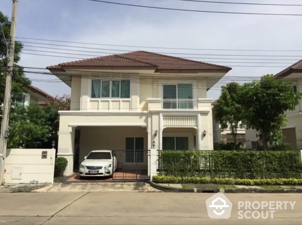 Charming two-story house with carport and lush greenery in a serene neighborhood.