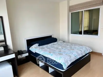 Spacious bedroom with modern furnishings and large window for natural light.