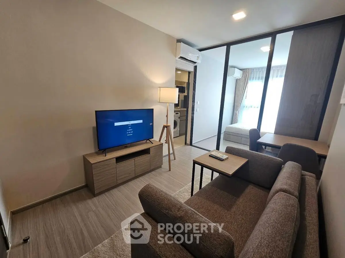 Modern living room with sleek furniture and open layout, featuring a cozy sofa and large TV for entertainment.