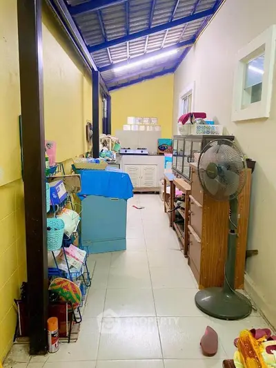 Spacious utility area with ample storage options, featuring a high ceiling, tiled flooring, and a well-ventilated space with a large fan and natural light.