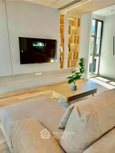 Modern living room with sleek design, built-in shelves, and large TV for ultimate comfort.