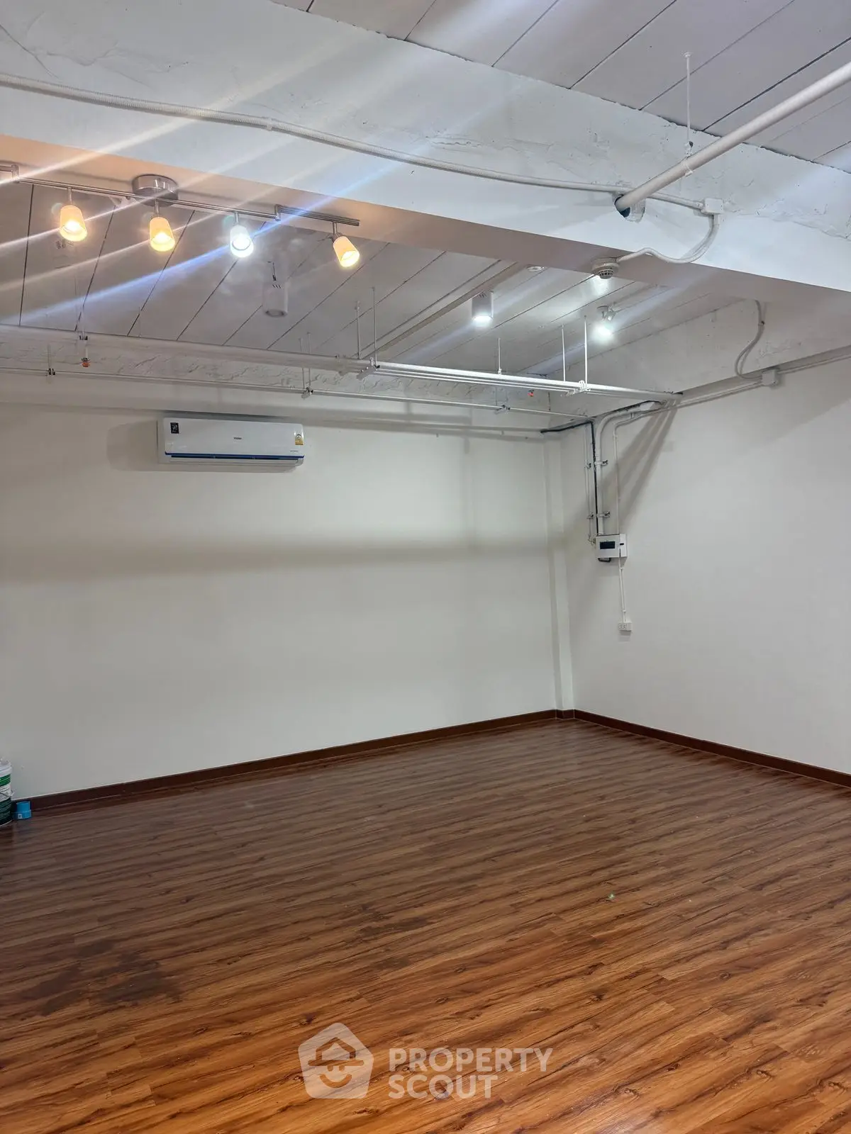 Spacious empty room with wooden flooring and modern lighting, ideal for customization.