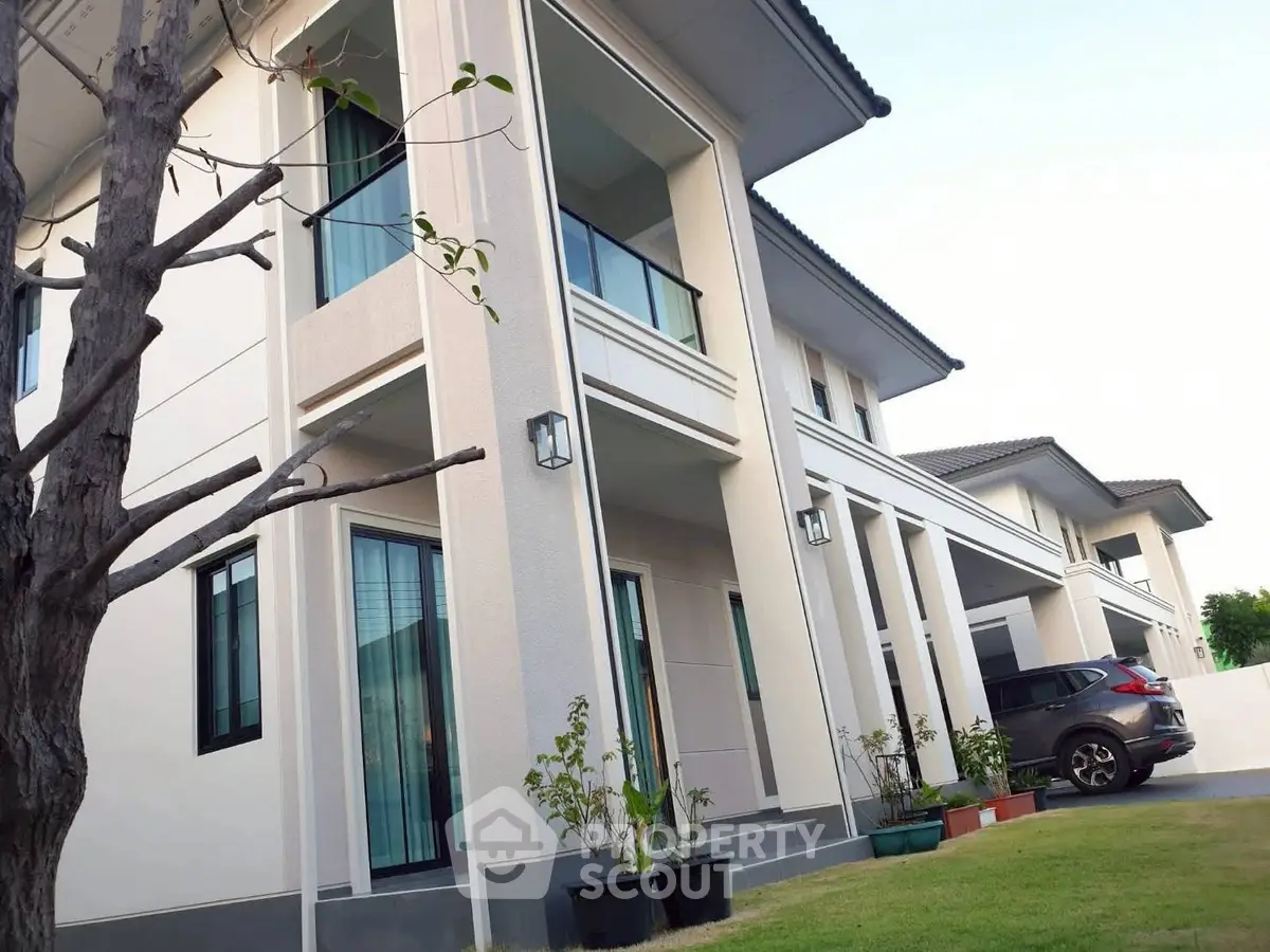 Modern two-story house with sleek design and lush green lawn, featuring large windows and a spacious driveway.