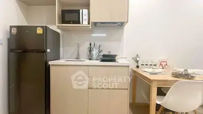 Modern compact kitchen with dining area, featuring sleek appliances and minimalist design.