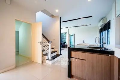 Modern open-plan kitchen with sleek design and staircase leading to upper floor
