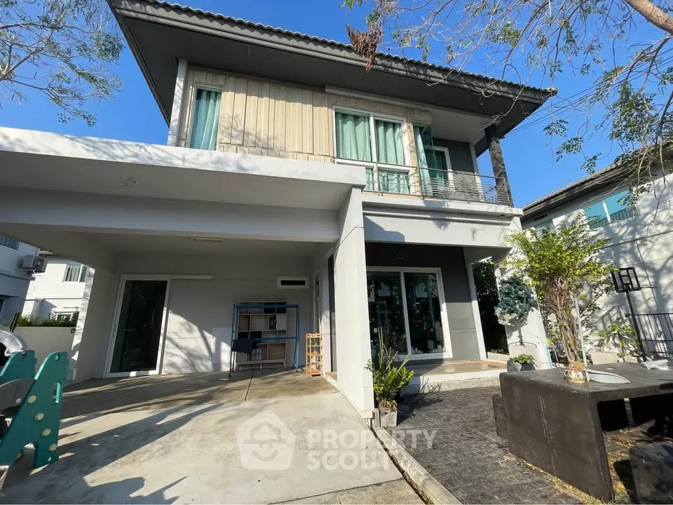Modern two-story house with large windows and spacious driveway in a serene neighborhood.