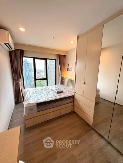 Modern bedroom with city view, featuring wooden flooring and built-in wardrobe.