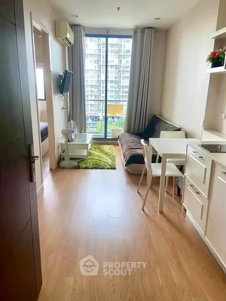 Modern apartment living room with wooden flooring and large window view.