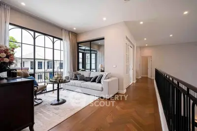 Elegant living room with large windows and stylish decor, featuring a cozy seating area and hardwood floors.