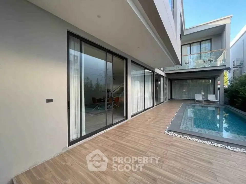 Modern luxury home with sleek poolside patio and glass doors.