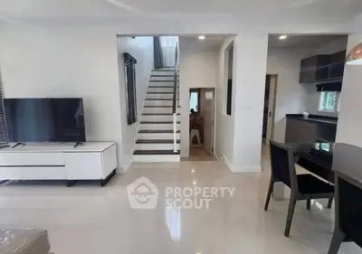 Modern interior with sleek staircase and open living area, featuring stylish furniture and contemporary design.