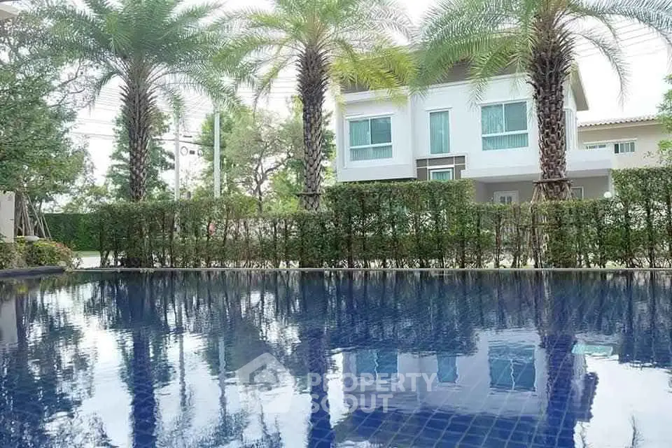 Luxurious home with a serene pool and lush greenery, perfect for relaxation.