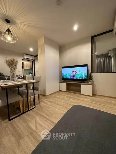Modern living room with stylish decor and open layout, featuring a cozy dining area and sleek TV setup.