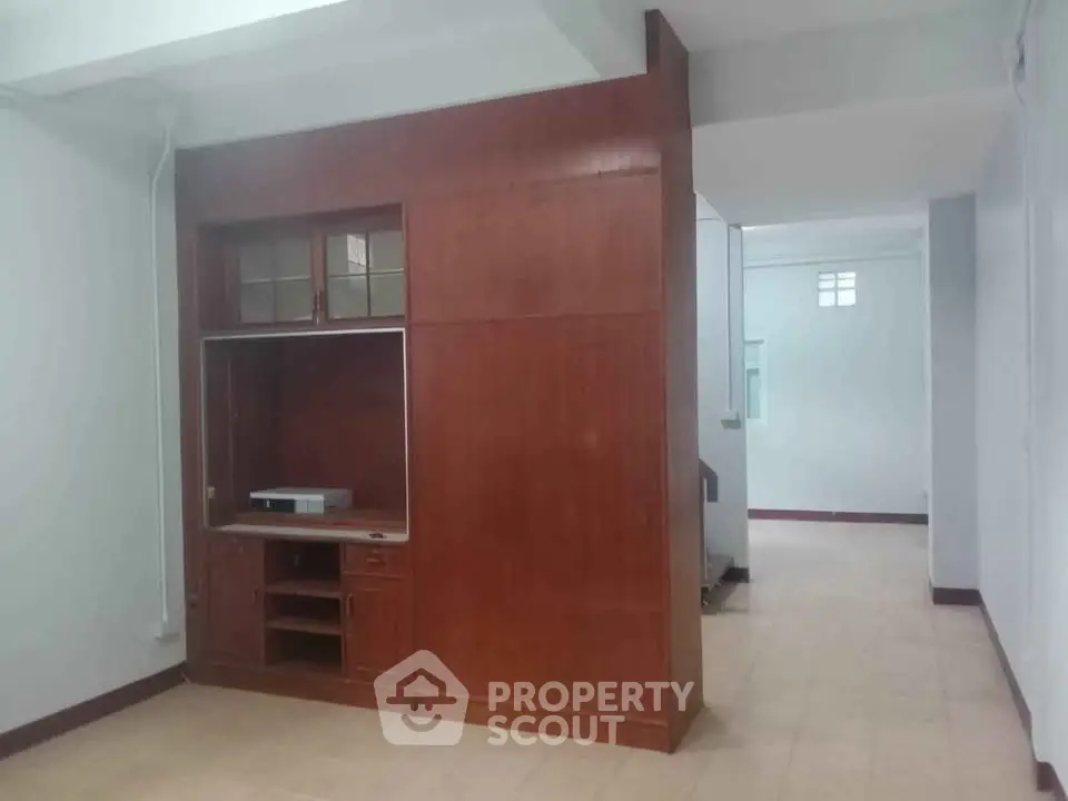Spacious interior with built-in wooden storage unit and tiled flooring, ideal for versatile living space.