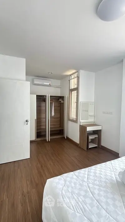 Spacious bedroom with wooden flooring and built-in wardrobe