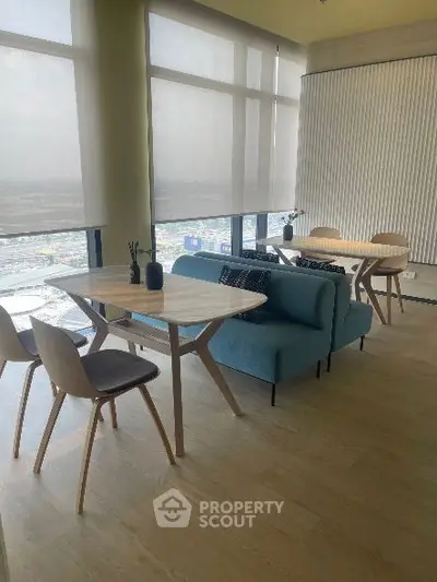 Modern living room with stylish furniture and large windows offering city views.