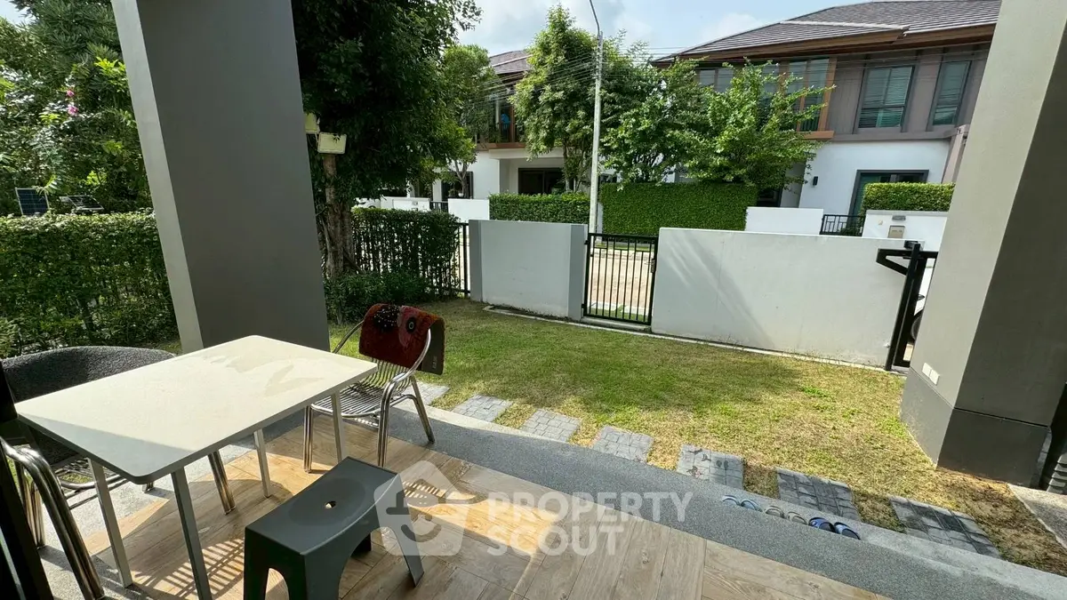 Charming garden view from a cozy patio with modern outdoor furniture.