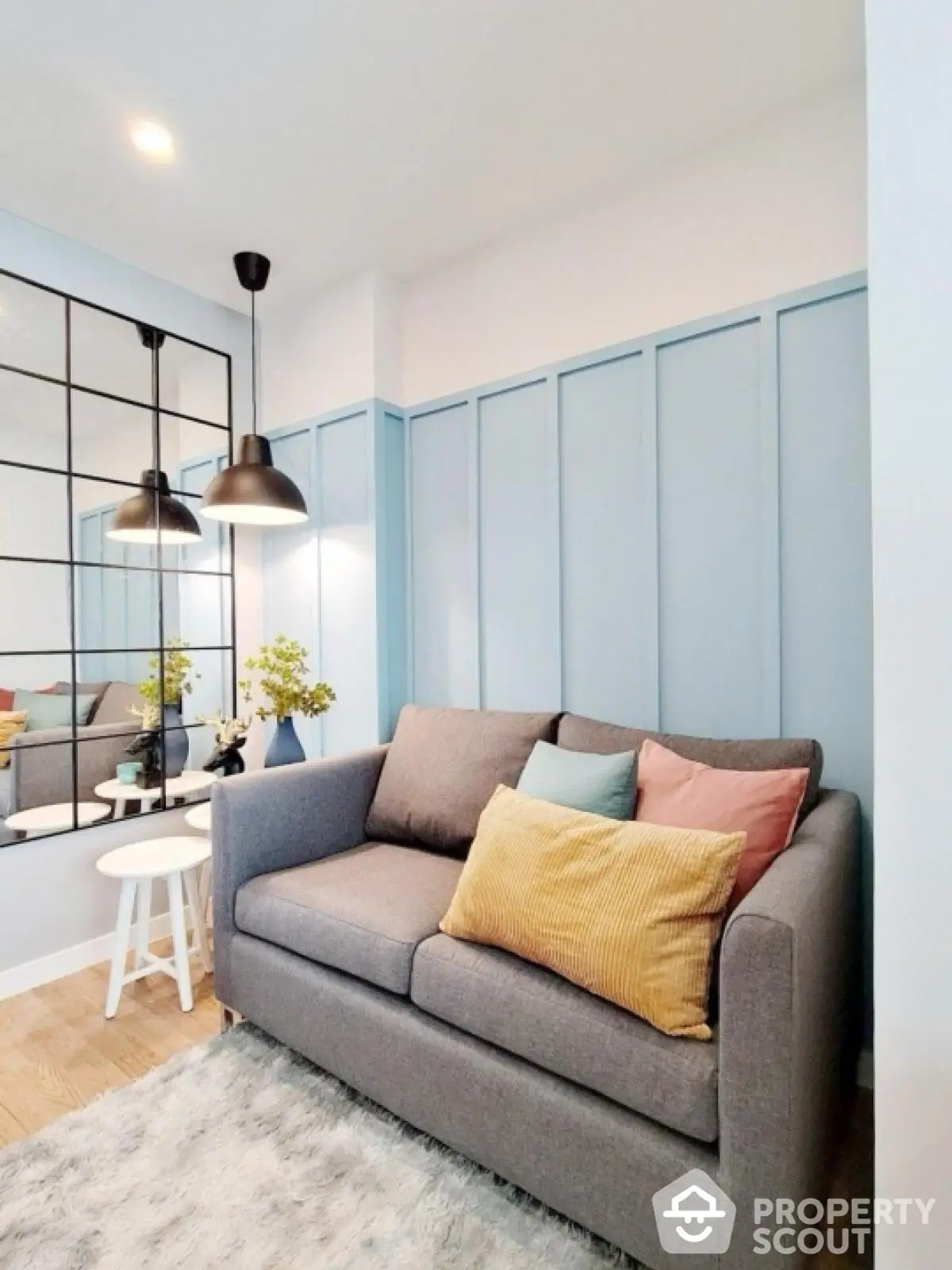 Charming living room with cozy sofa, stylish lighting, and decorative mirror wall.