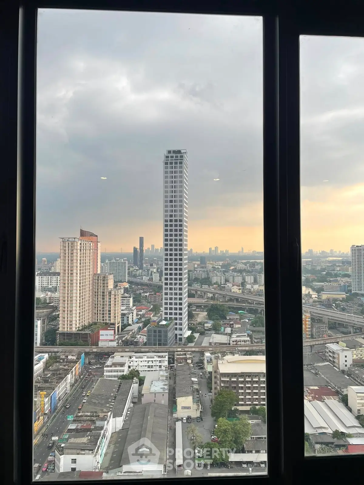 Stunning cityscape view from high-rise window showcasing urban skyline at sunset.