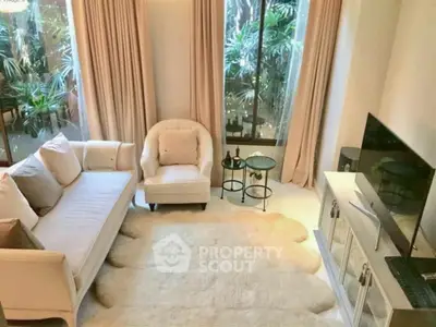 Elegant living room with plush seating and large windows overlooking lush greenery.