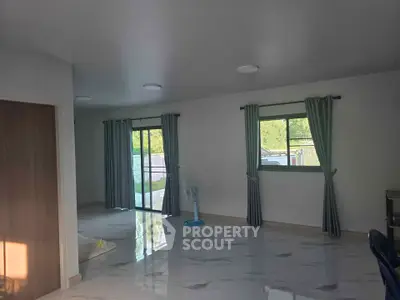 Spacious living room with large windows and elegant curtains, featuring glossy tiled floors and a serene outdoor view.