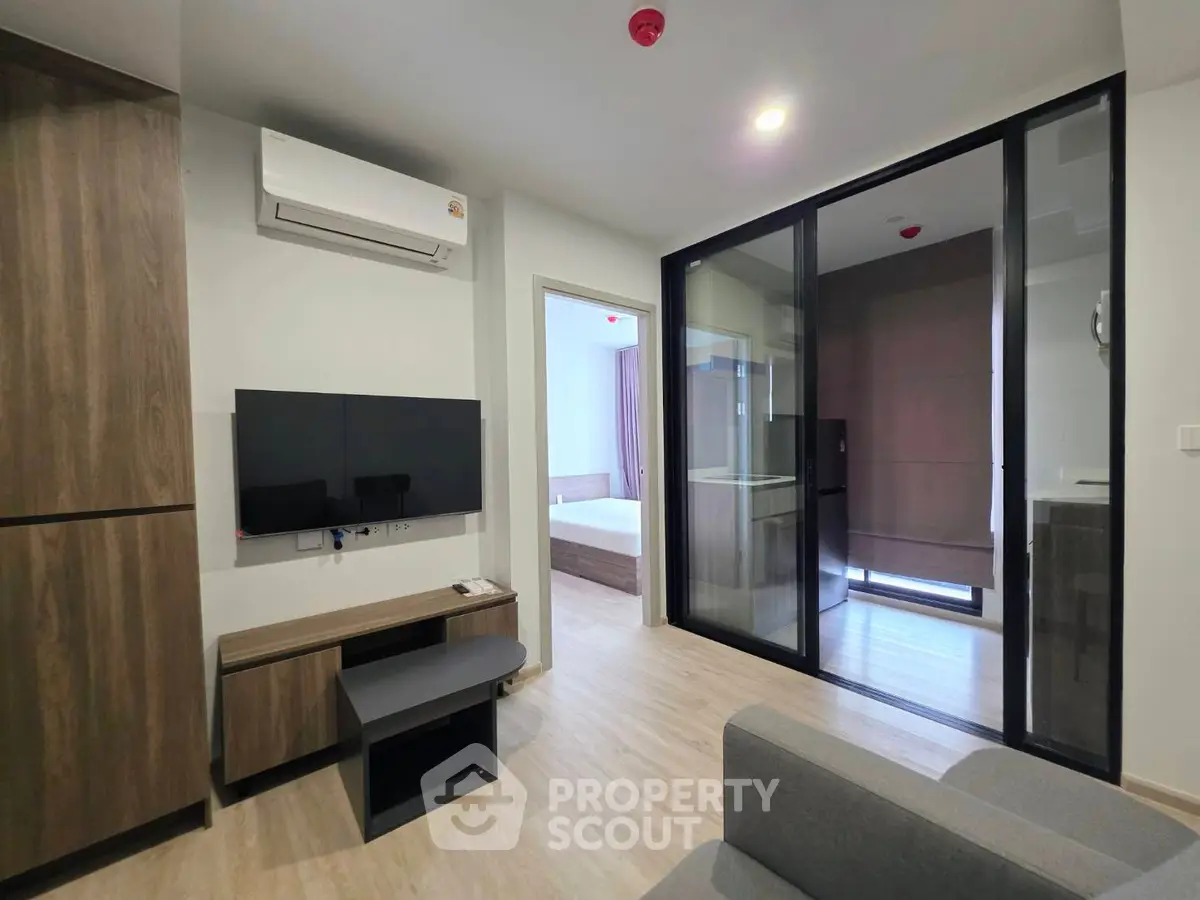 Modern apartment interior with sleek design, featuring a cozy living area and a glimpse of the bedroom.