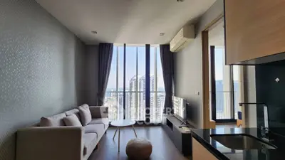 Modern living room with stunning city view, featuring sleek furniture and floor-to-ceiling windows.