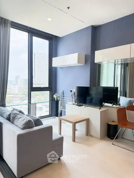 Modern living room with large windows and city view, featuring sleek furniture and stylish decor.