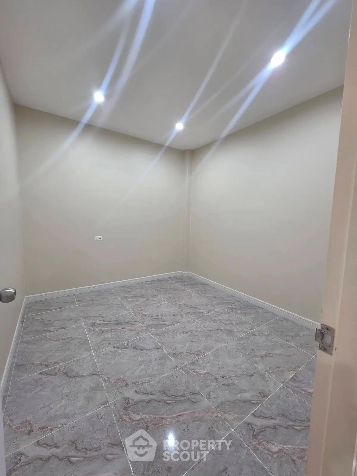 Spacious empty room with modern tile flooring and recessed lighting, perfect for customization.