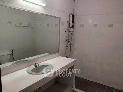 Spacious bathroom with large mirror and modern fixtures in a real estate property.