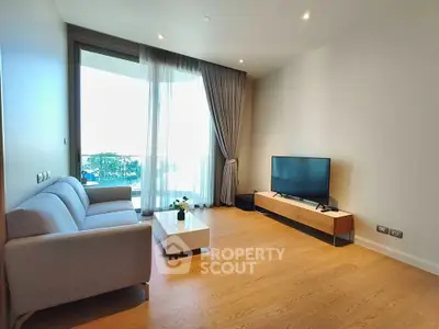 Modern living room with sleek furniture and large window offering natural light and balcony access.