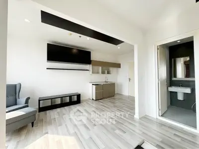 Modern open-plan living room with sleek flooring and compact kitchen area.