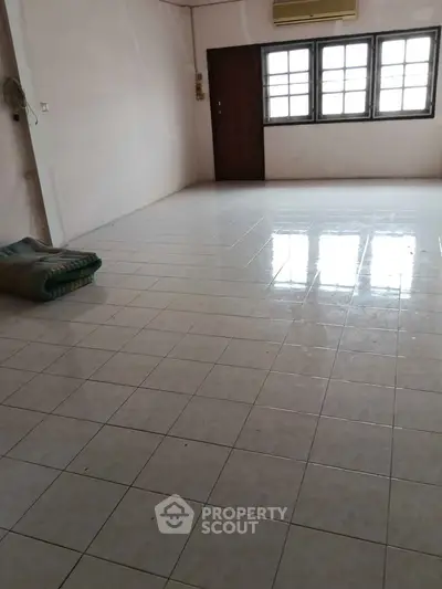 Spacious empty room with tiled flooring and large windows, ideal for customization.