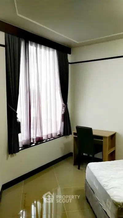Cozy bedroom with natural light, featuring a comfortable bed and a study desk by the window.