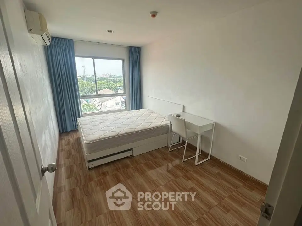 Spacious bedroom with large window and modern furnishings, offering a serene view.