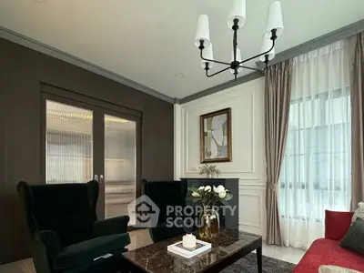 Elegant living room with dark armchairs, marble coffee table, and modern chandelier.