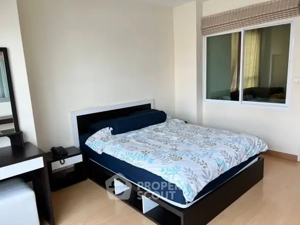 Spacious bedroom with modern furnishings and large window for natural light.