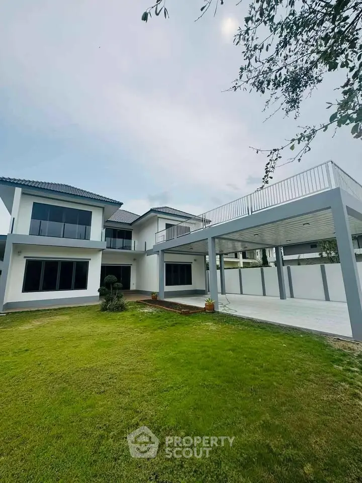 Stunning modern two-story house with spacious lawn and covered parking area.