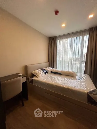 Modern bedroom with large window and natural light in a stylish apartment.