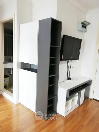Modern living room with sleek storage and wall-mounted TV, featuring elegant wooden flooring.