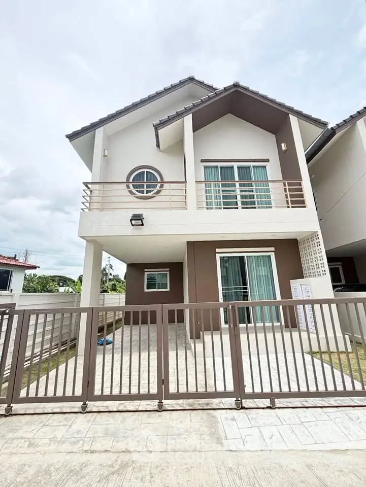 Modern two-story house with balcony and gated entrance in a suburban neighborhood.
