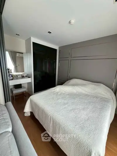 Cozy bedroom with modern design, featuring a large bed, built-in wardrobe, and stylish vanity area.