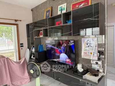 Modern living room with sleek entertainment center and large TV, showcasing stylish decor and natural light.