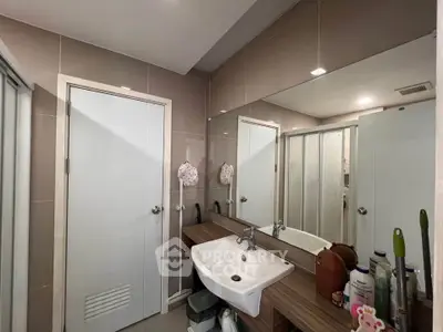 Modern bathroom with sleek design, featuring a large mirror, stylish sink, and ample storage space.